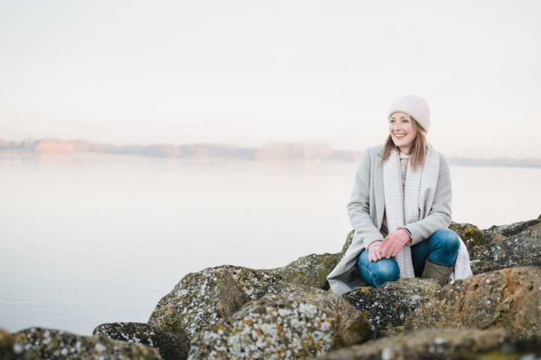 lady sat in grey coat looking out at rutland water for brand photos