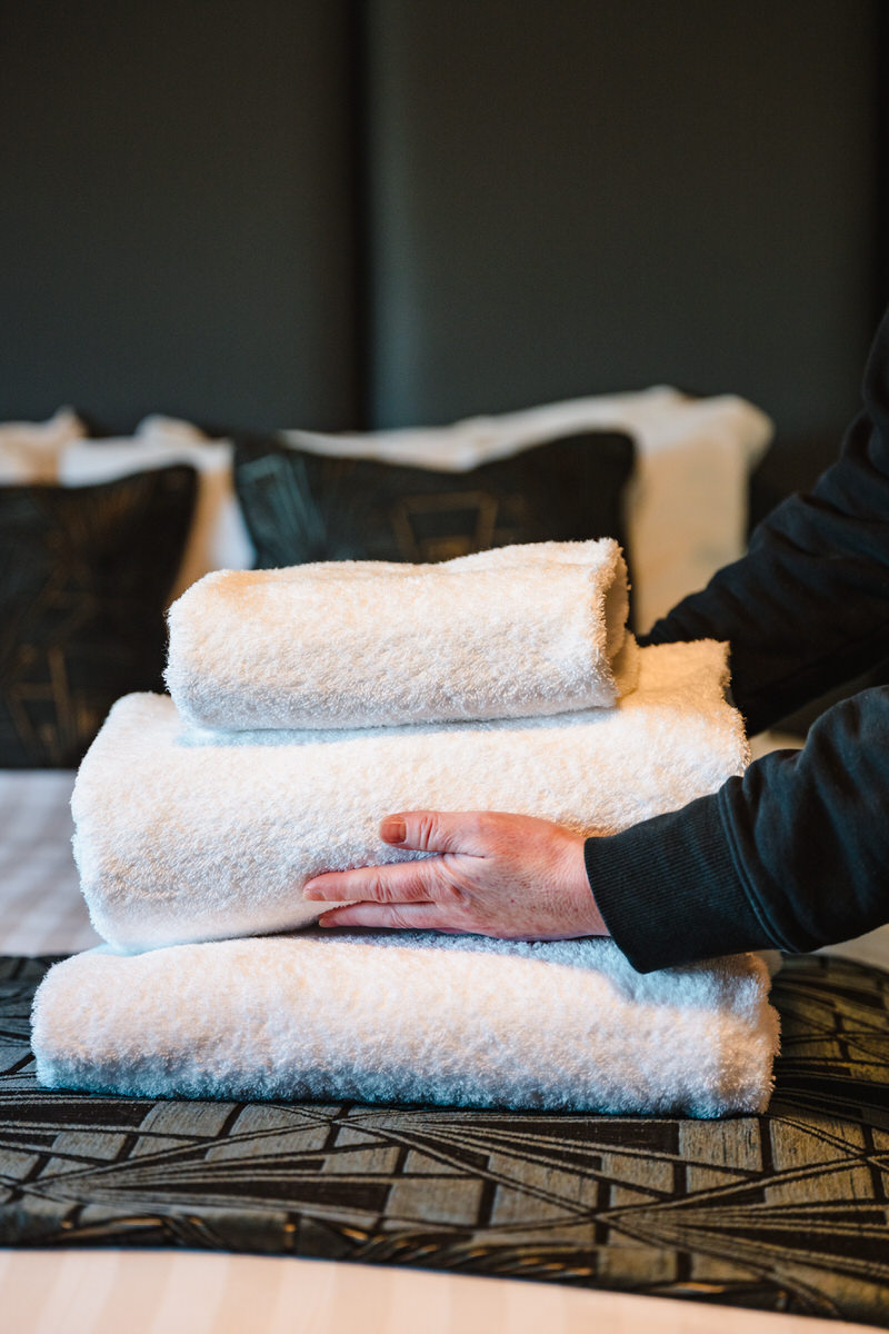 Business Photography for a hotel image of cleaner putting towels on bed